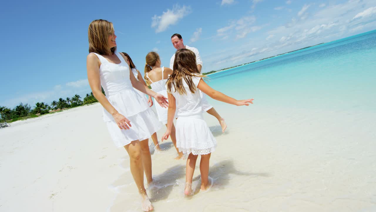 Caucasian family in white clothes walking on beach