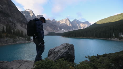 tourist photographer capturing scenic view with mountainscape at background in moraine lake, alberta, canada