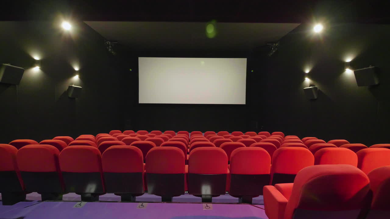 viajando sobre la fila de asientos del cine rojo con la pantalla en el fondo. cine