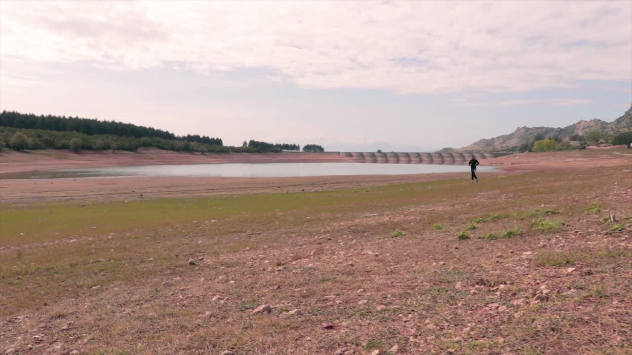 hombre corriendo en una playa de un pequeño lago