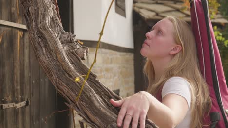 Young-woman-gentle-hands-caress-aged-vine-tendril,-tactile-nature