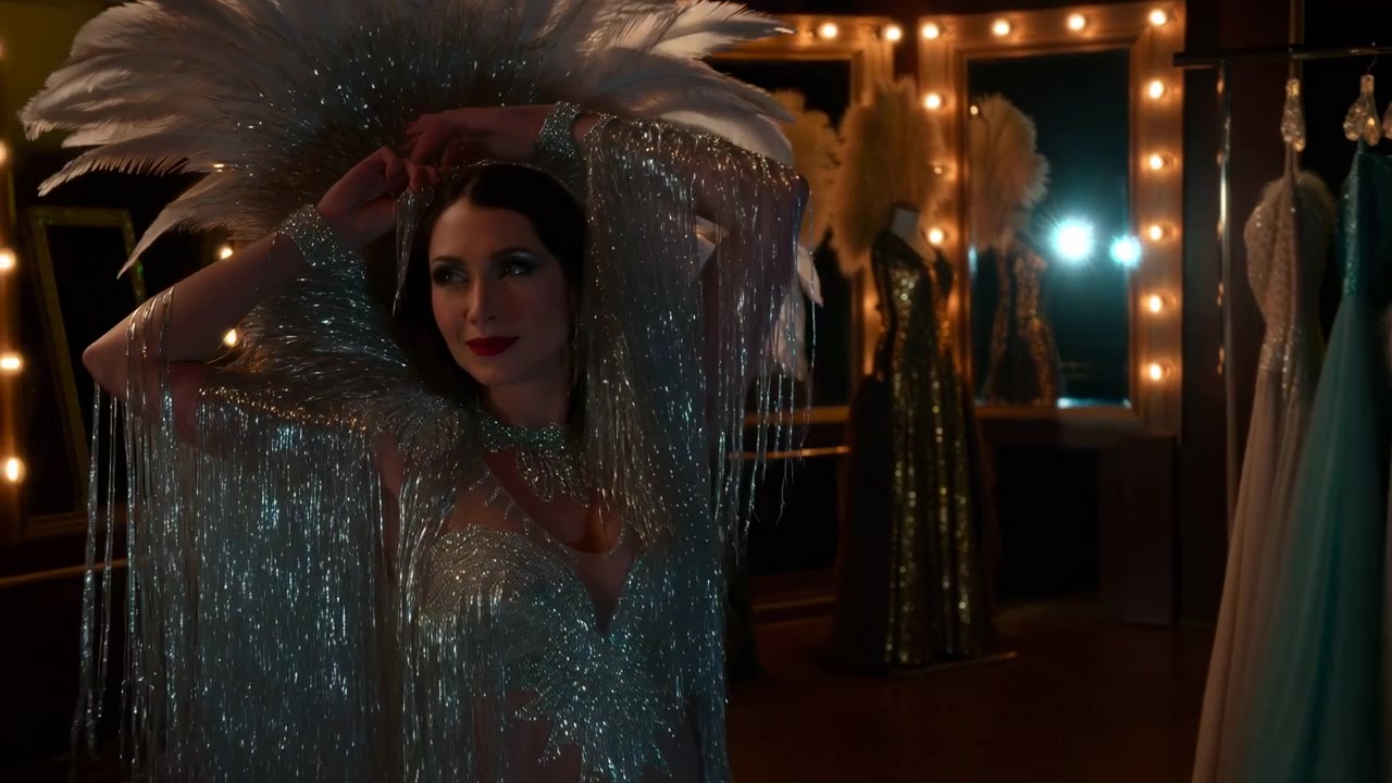 Sparkling Cabaret Dressing Room Showgirl Adjusts Sequin Headdress Under Mirror Lights Feathered Costume