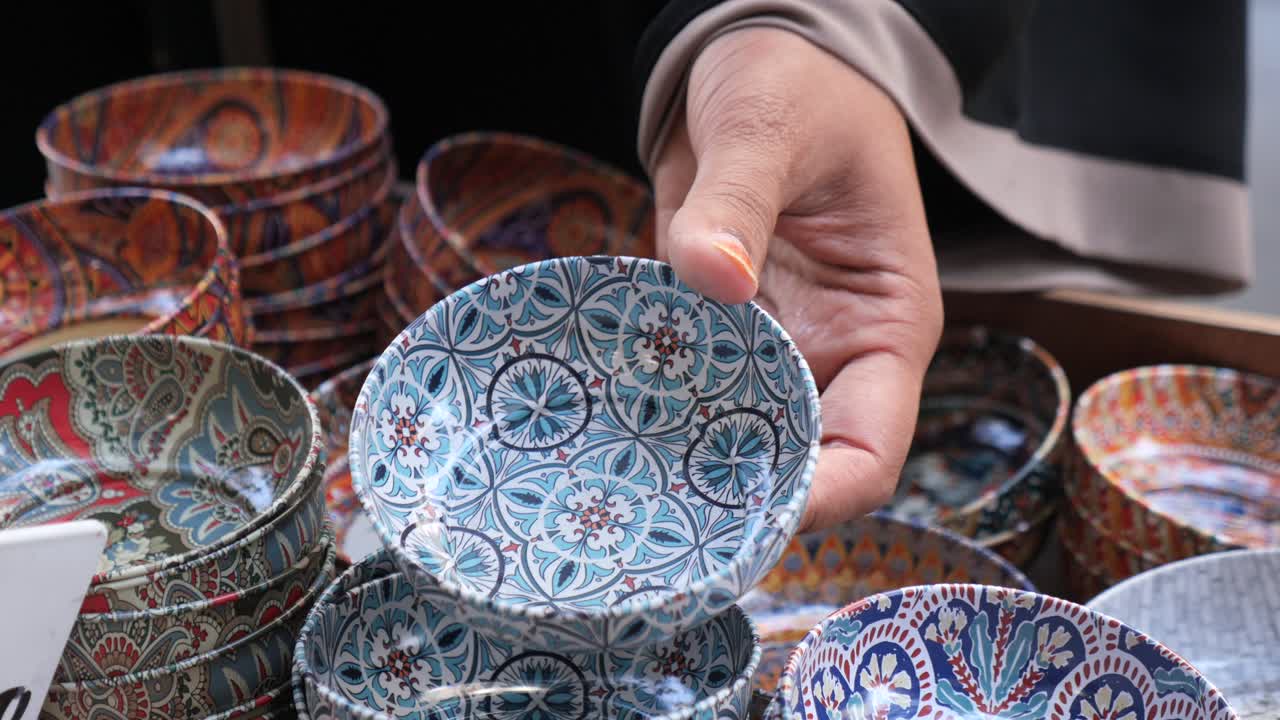 Hand selecting a decorative patterned bowl from a display