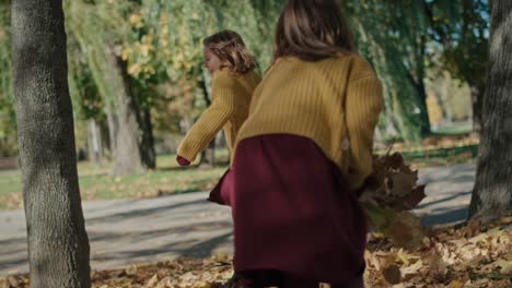 caucasian child siblings having fight with leaves in the autumn park.