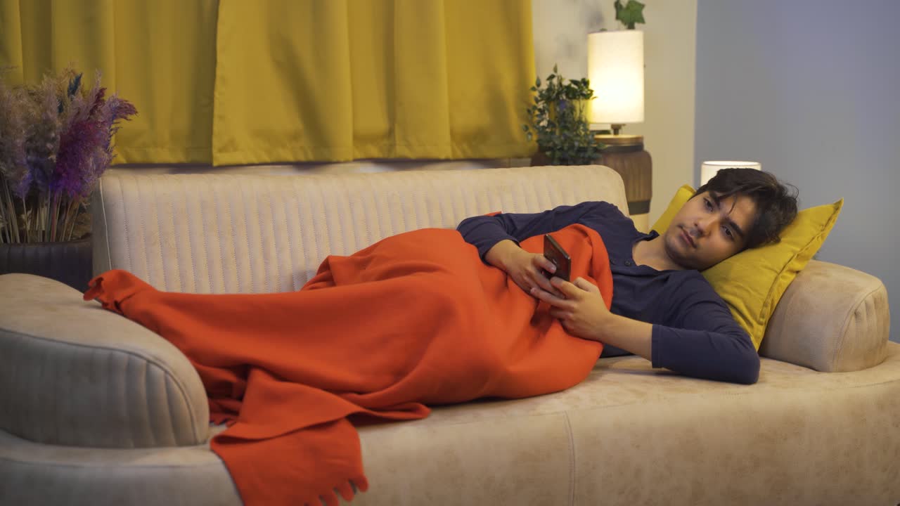 침대에서 전화로 문자 메시지를 보내는 남자.