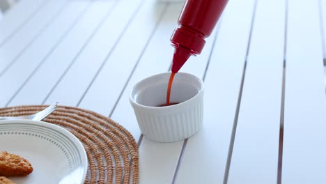 pouring ketchup over fries on a table