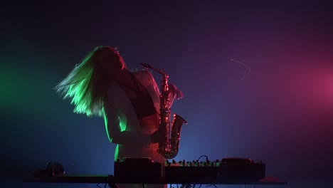 woman playing saxophone and djing on a stage