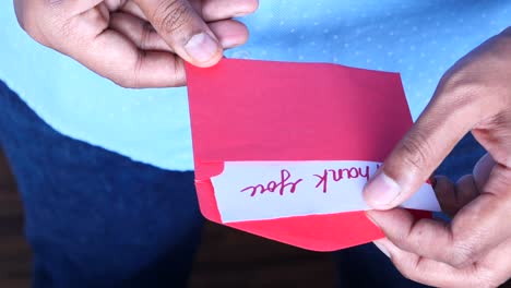 person opening a red envelope with a thank you note