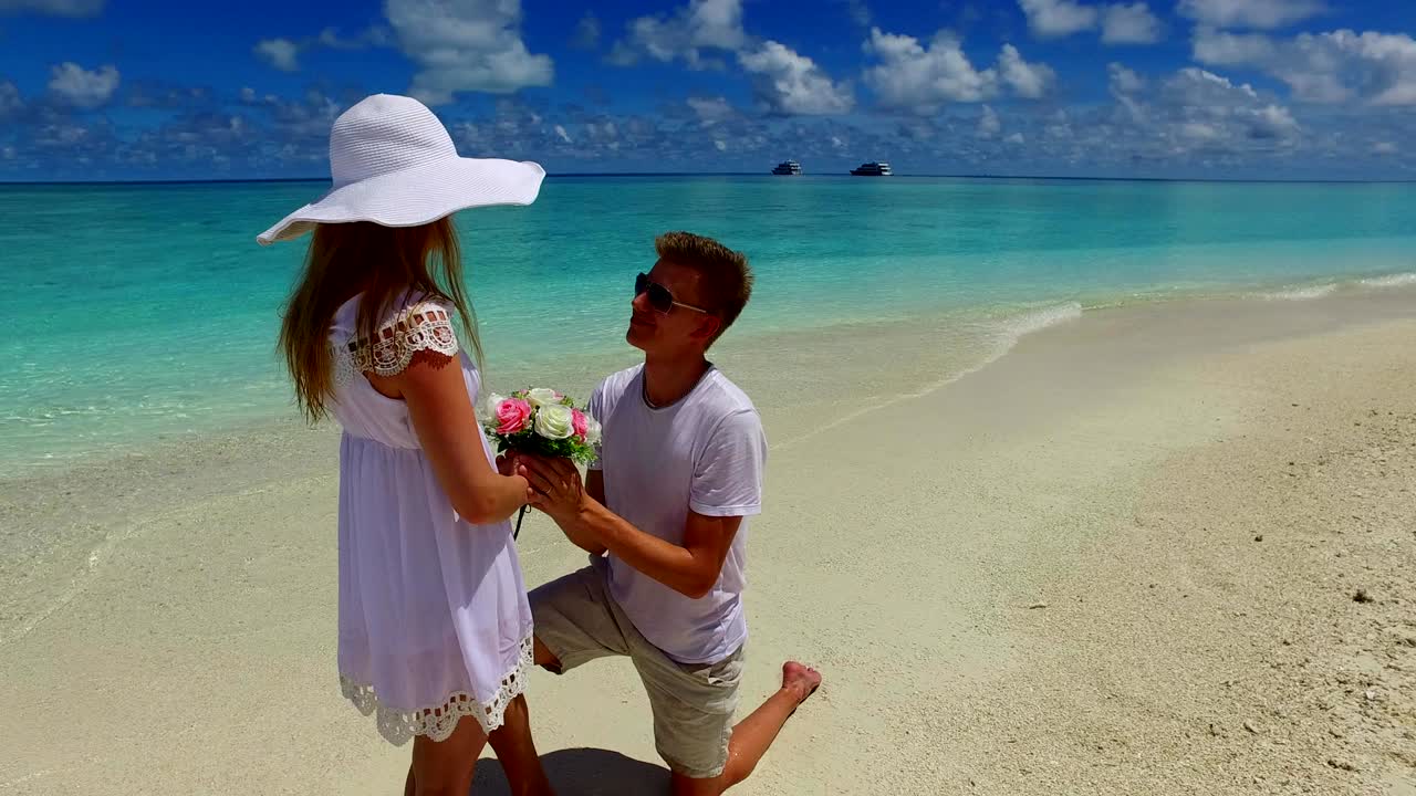 v07388 Malediven wit zandstrand 2 personen jong stel man vrouw aanzoek verloving bruiloft huwelijk op zonnig tropisch paradijselijk eiland met aquablauwe lucht zeewater oceaan 4k