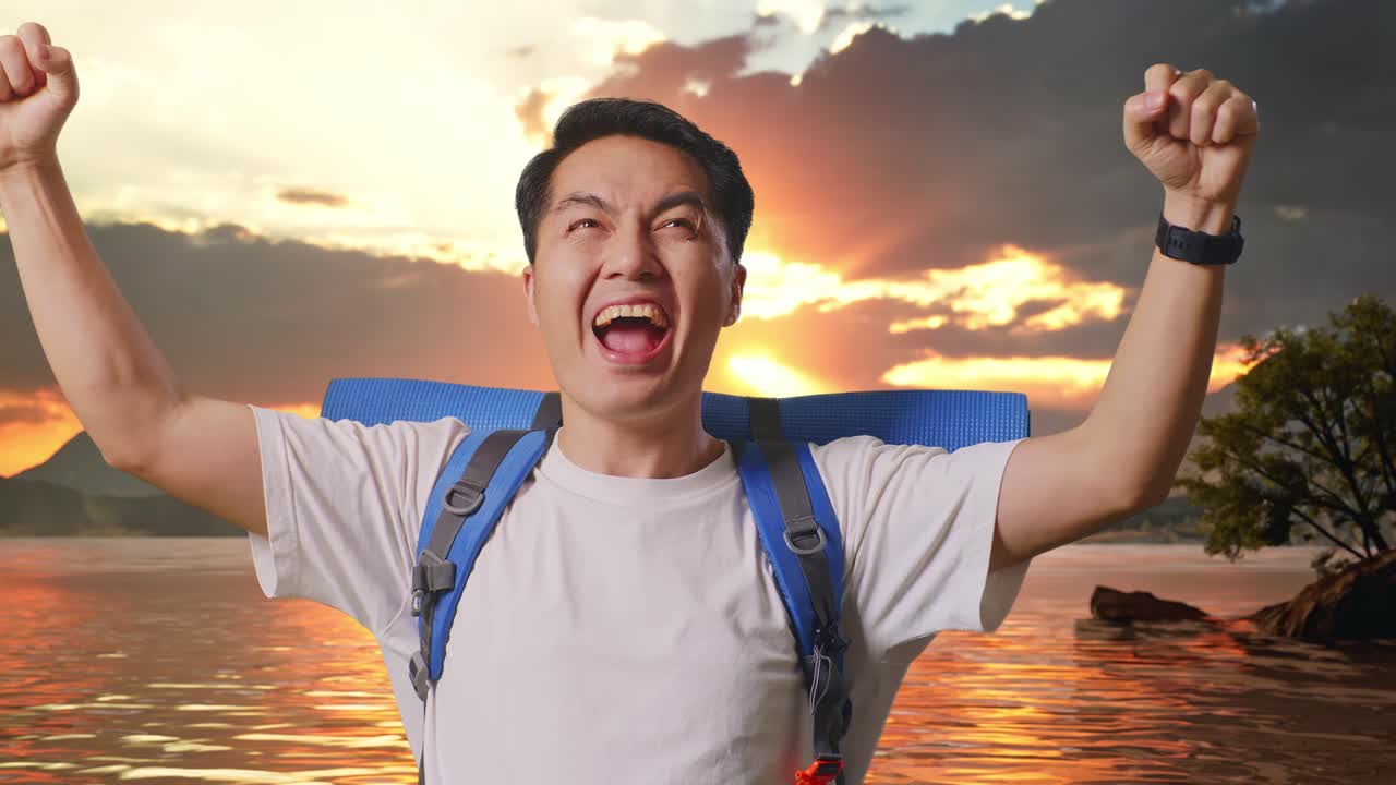Close Up Of Asian Male Hiker With Mountaineering Backpack Screaming Goal Celebrating The Success At A Lake