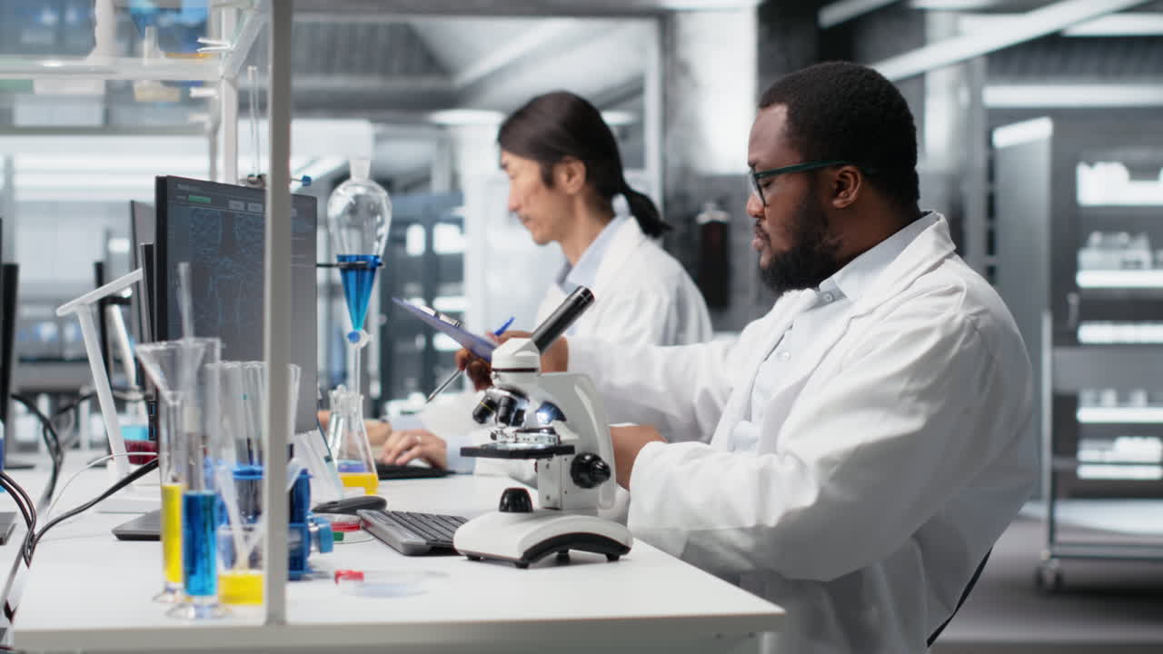 Vertical video Researcher operating microscope, doing observations in laboratory, writing notes