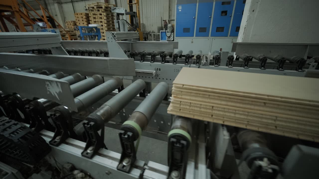 Træplanker bevæger sig på automatiseret transportbånd på fabrik.