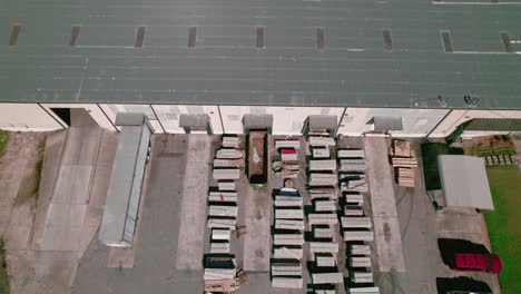 forklift worker exiting a warehouse with rows stacks of vinyl siding building material construction