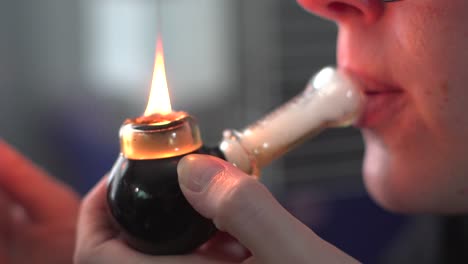 primer plano de los labios de una mujer inhalando marihuana medicinal a través de una pipa