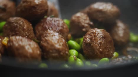 unrecognizable person cooking green beans and meatballs