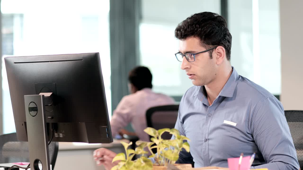 un joven empleado de oficina o empleado que trabaja en una computadora en una oficina moderna. un joven y guapo hombre de negocios