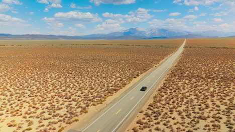 following the black cars riding by the empty road through the deserted land. highway from california to nevada footage on sunny day. mountain at backdrop.