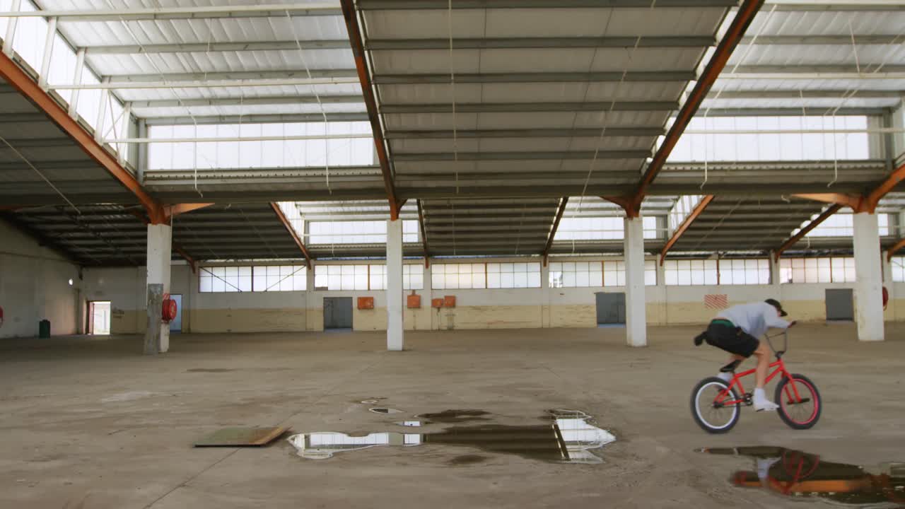 Ciclista BMX in un magazzino vuoto.