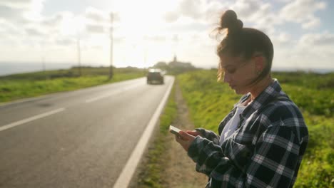 mujer usando el teléfono al lado de la carretera