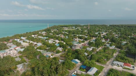 an aerial view of a village near the coast with buildings and tropical trees