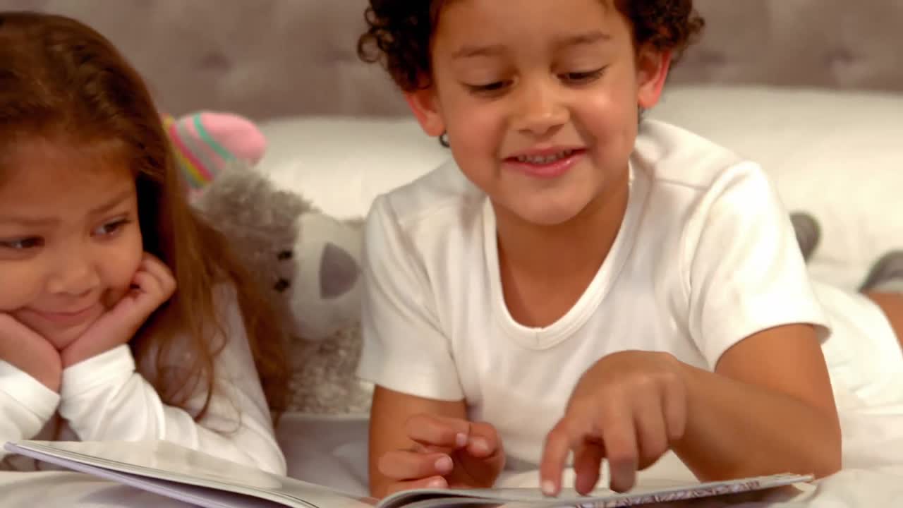 Bambini ispanici che leggono un libro insieme