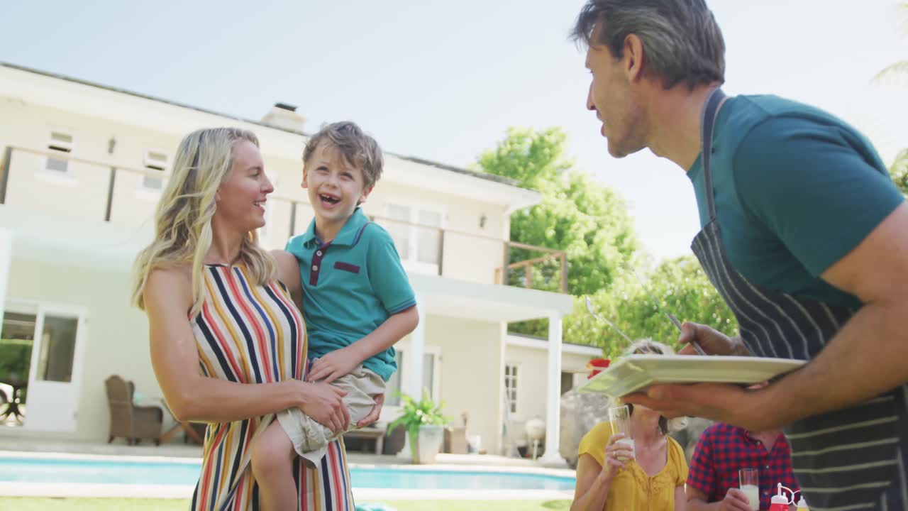 행복 한 백인 가족 이 정원 에서 바베큐 를 하고 식사 하고 있다