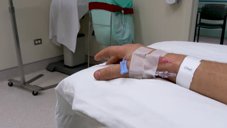 slow moving hand movements of unrecognizable caucasian male right hand in medical scenario with iv in wrist