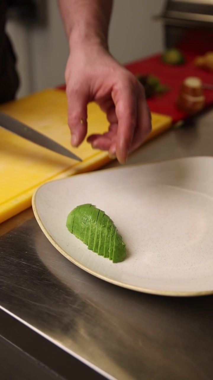 Chef Plating Freshly Sliced Avocado in a Professional Kitchen