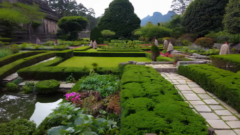 monks meditating in a tranquil formal garden with pond and mountains