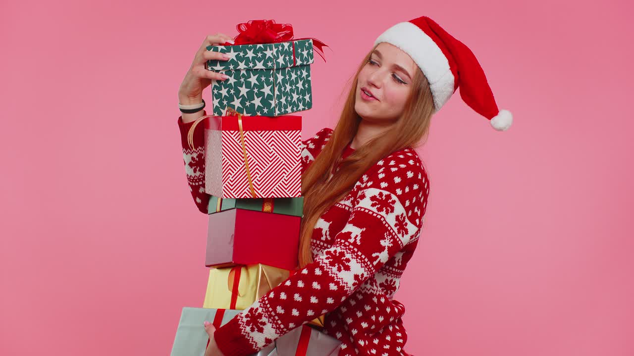 Girl in christmas red sweater santa hat smiling holding many gift boxes new year presents shopping