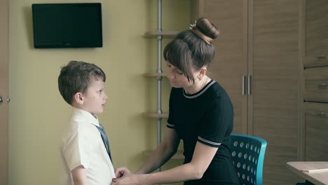 mother dresses a child to school straightens his clothes 1