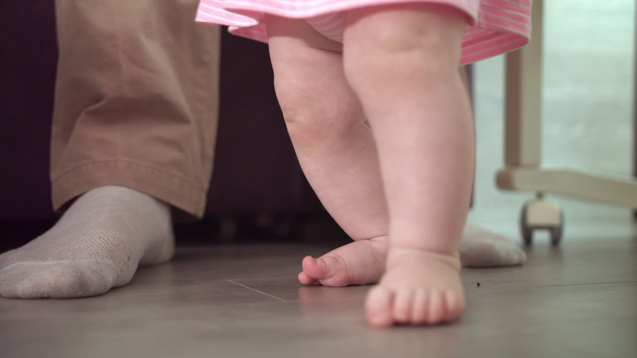los pies del bebé aprenden a caminar. concepto de apoyo de los padres. pequeños pasos en el hogar