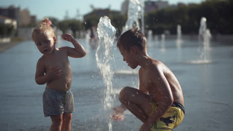 siblings play with a fountain