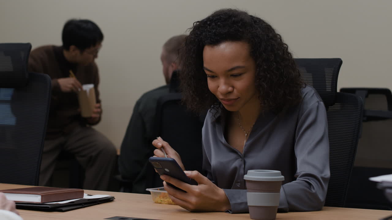 Woman eating lunch in office while using phone