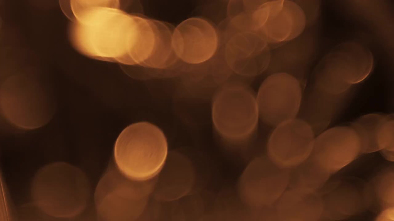 Particelle Bokeh Astratte di Luce Dorata Fluttuanti su Sfondo Scuro