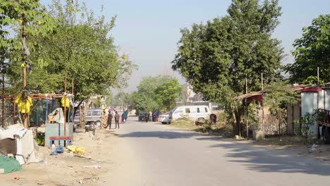 a rural street scene in a neighborhood of a pakistani city, showcasing animal stores and pedestrians.