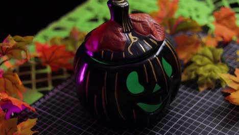 Black-pumpkin-Halloween-decoration-with-green-eyes,-close-up