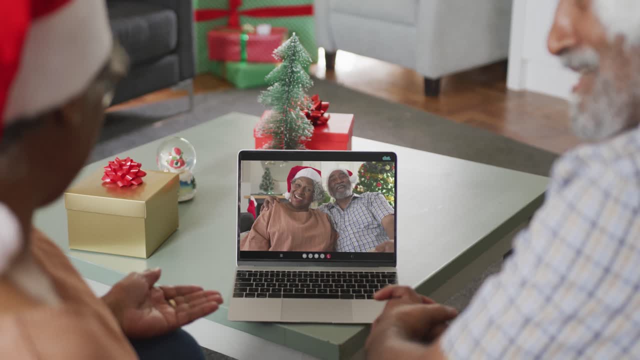 feliz pareja afroamericana en videollamada en computadora portátil con amigos mayores en tiempo de navidad