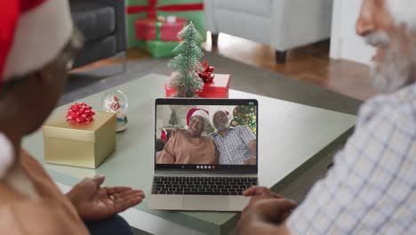 Glückliches-Afroamerikanisches-Paar-Bei-Einem-Videoanruf-Auf-Dem-Laptop-Mit-älteren-Freunden-Zur-Weihnachtszeit