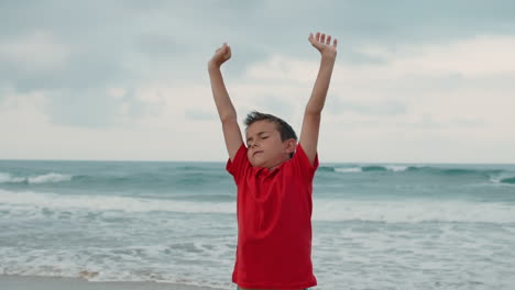 carefree boy spending summer at seaside. happy guy stretching at beach.