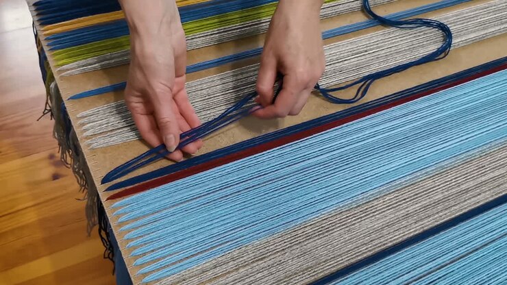Penenun memasang benang wol ke papan tenun untuk pembuatan tekstil