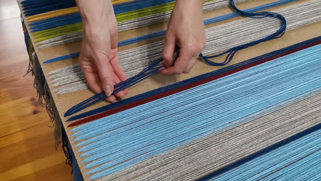 weaver attaching wool yarns to a weaving board for textile making