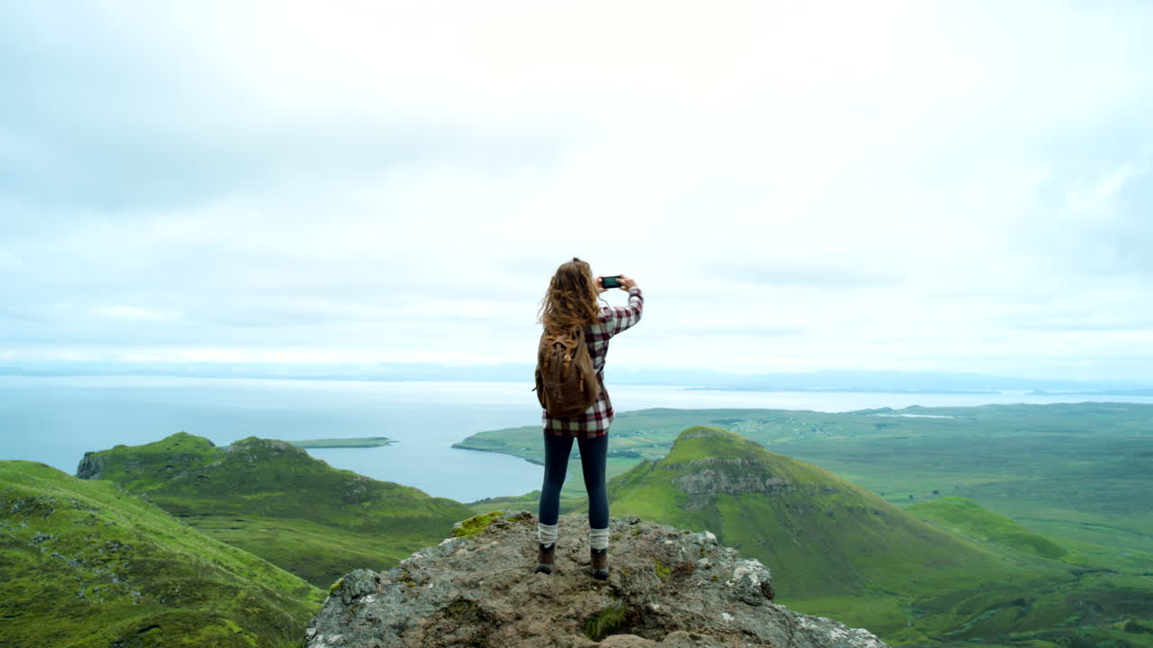 mujer caminando y tomando fotos de paisajes panorámicos