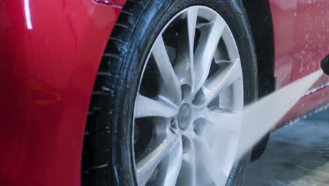 car washing cleaning with foam and high pressured water. red car