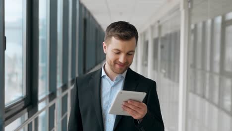 smiling young man walking down the hall with a tablet