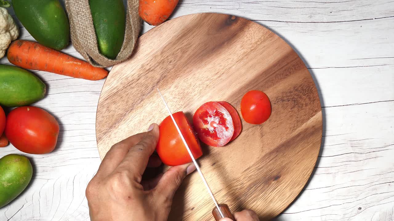 채소와 함께 나무로 만든 절단판에 토마토를 잘라내는 것