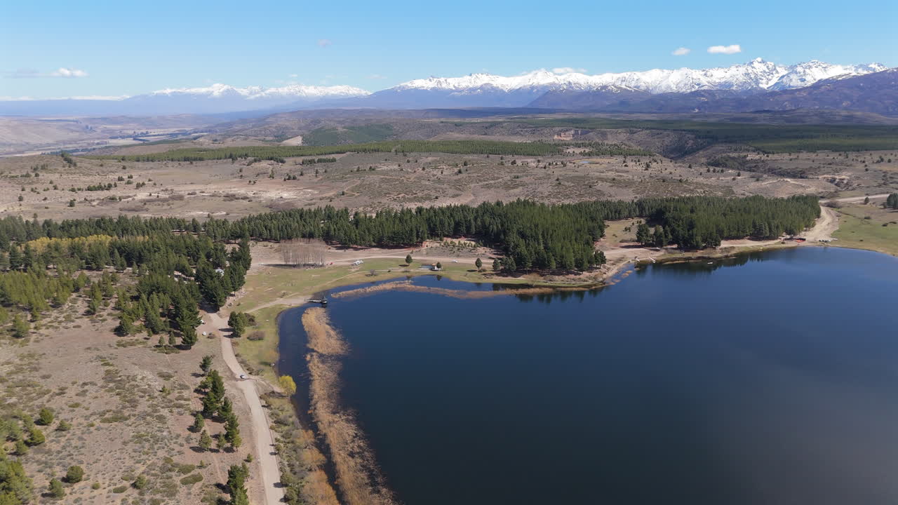 широкоугольный дронный снимок лагуны в городе эскель, южная аргентина. цвет воды контрастирует с деревьями и заснеженными горами на задней стороне. 4k-60fps.