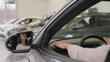 mujer eligiendo un coche en una sala de exposición de automóviles