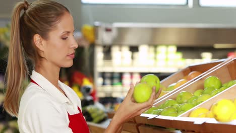 pretty worker stocking the fruit in supermarket