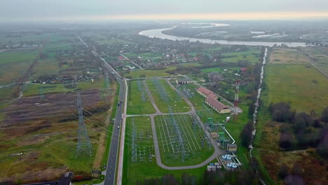 Aerial-drone-rotating-shot-flying-voer-a-high-voltage-power-distribution-substation-beside-a-highway-on-a-cloudy-day